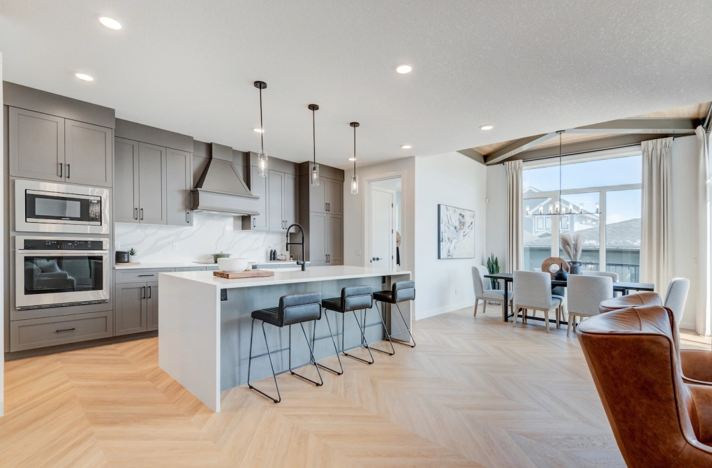 Depicts a clean white kitchen with grey cabinets and an island with seating.